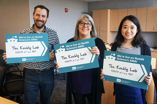 Three researchers hold a reddit sign