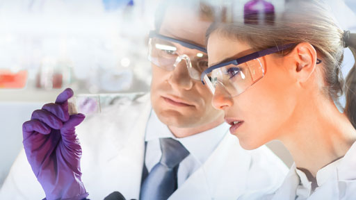 Scientists in lab looking at vial