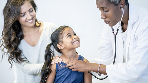 African American doctor checking little girl's heartbeat