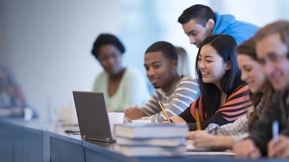 Diverse group of students in front of a laptop